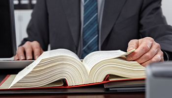 Attorney reviewing a large open law book at a desk.